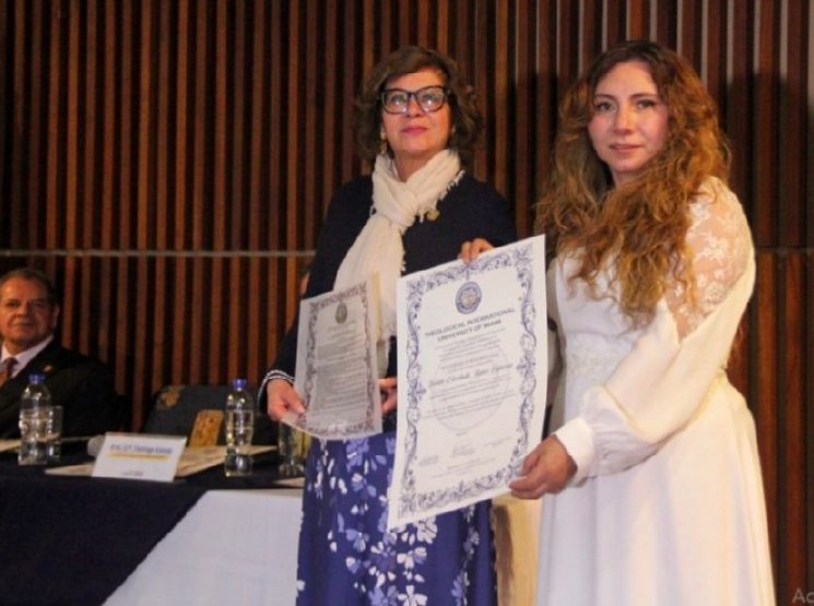 Dos mujeres sosteniendo sus certificados en una ceremonia