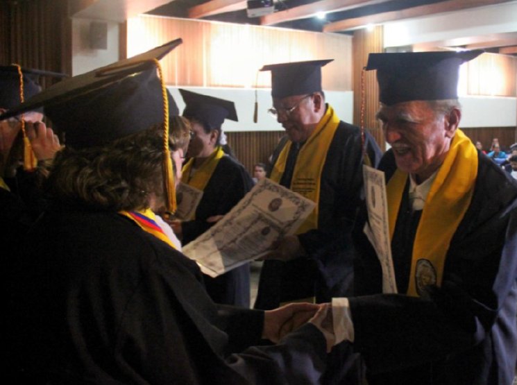 Entrega de un diploma con apretón de manos entre dos personas con toga